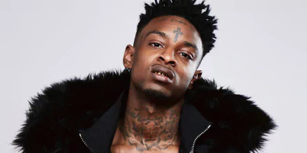 HD desktop wallpaper featuring a photo of a man with tattoos and a fur-collared jacket, tagged as 21 Savage.