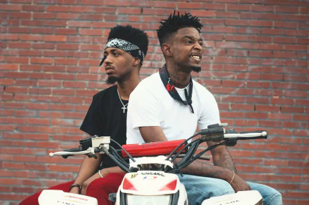 HD desktop wallpaper featuring two individuals on a motorbike against a brick wall background, tagged with 21 Savage.