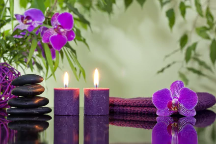 HD desktop wallpaper of a tranquil spa scene with purple orchids, stacked stones, and lit candles reflecting on a glass surface.