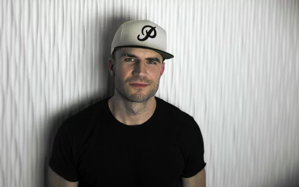 HD desktop wallpaper featuring a man in a cap and black shirt against a striped background.