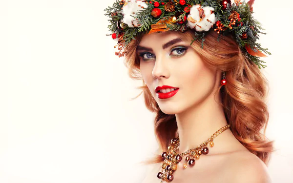 HD desktop wallpaper of a redheaded woman with blue eyes wearing a festive wreath, striking red lipstick, and a stylish necklace, smiling confidently.