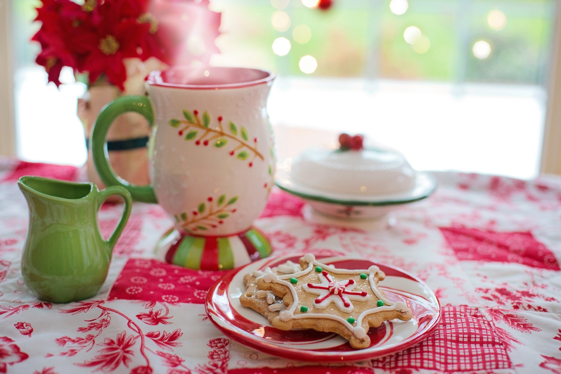 A 4K Ultra HD still life of Christmas cookies on a plate with a festive mug and creamer on a red and white tablecloth, creating a cozy holiday food scene.
