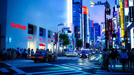 HD desktop wallpaper of a bustling Shinjuku street in Tokyo at twilight with neon signs and crowds.
