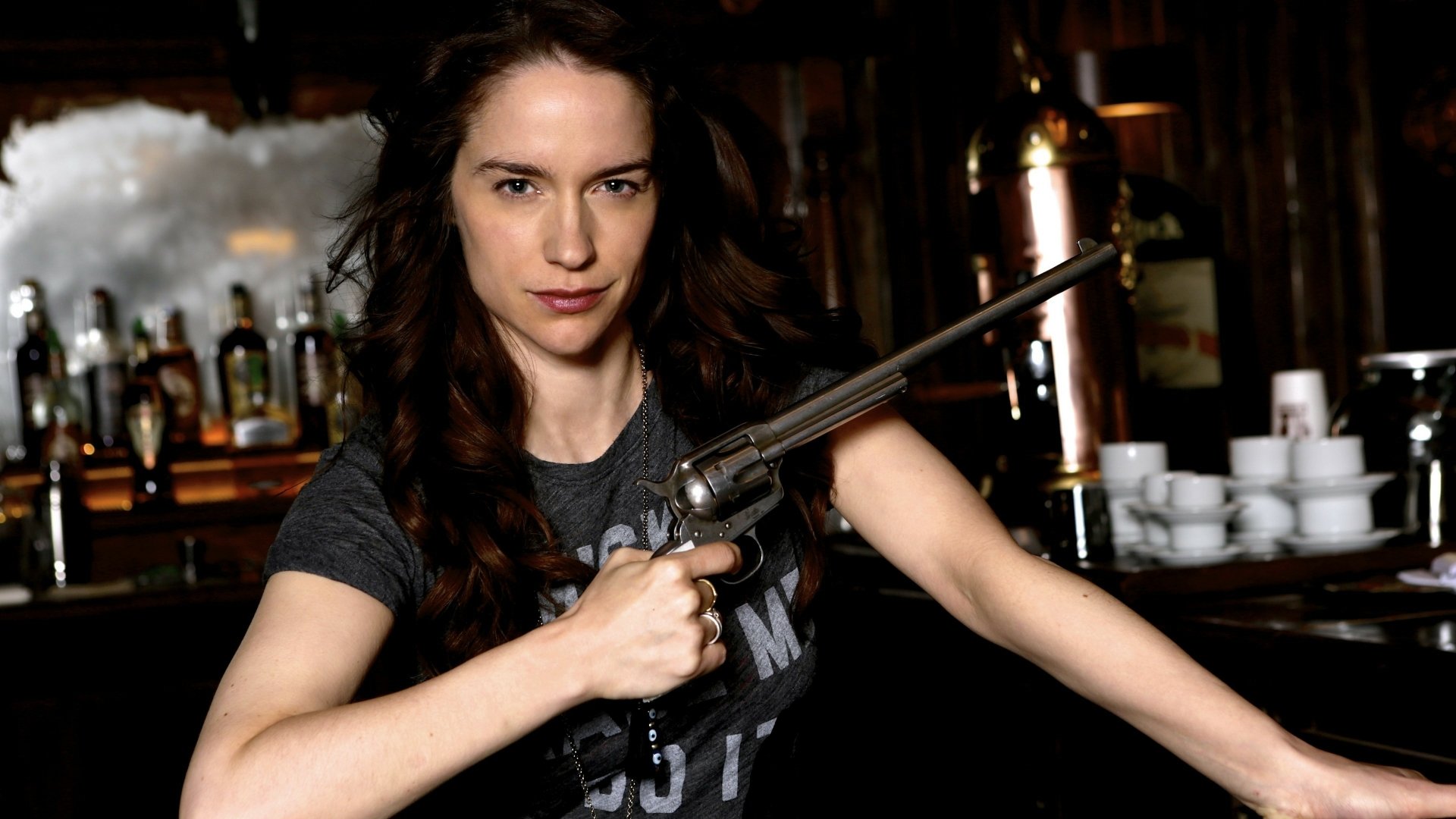 High-resolution 4K Ultra HD desktop wallpaper featuring a confident woman holding a revolver from the TV show Wynonna Earp in a dimly lit bar setting.