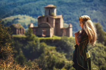 HD PC desktop wallpaper featuring a woman in detailed cosplay attire standing thoughtfully with an ancient stone building and lush green hills in the background.