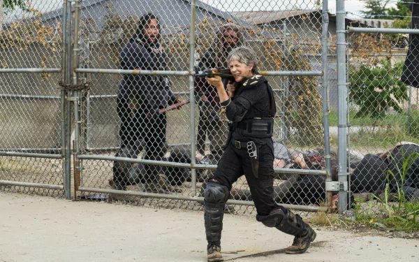 Ezekiel (Khary Payton) and Carol Peletier (Melissa Mcbride) from The Walking Dead walk near a chain-link fence in a 4K UHD TV show wallpaper.