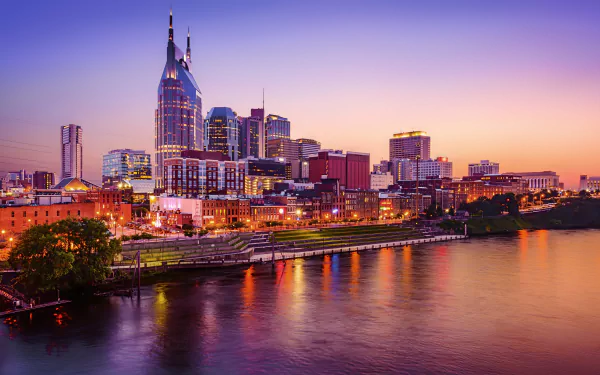 A stunning 4K Ultra HD desktop wallpaper of Nashville’s skyline at sunset, showcasing man-made structures reflected on the water against a vibrant evening sky.