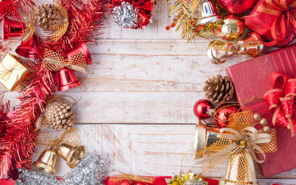 Festive 4K Ultra HD wallpaper featuring Christmas ornaments, pine cones, bells, baubles, gifts, and holiday decorations arranged on a rustic wooden background.