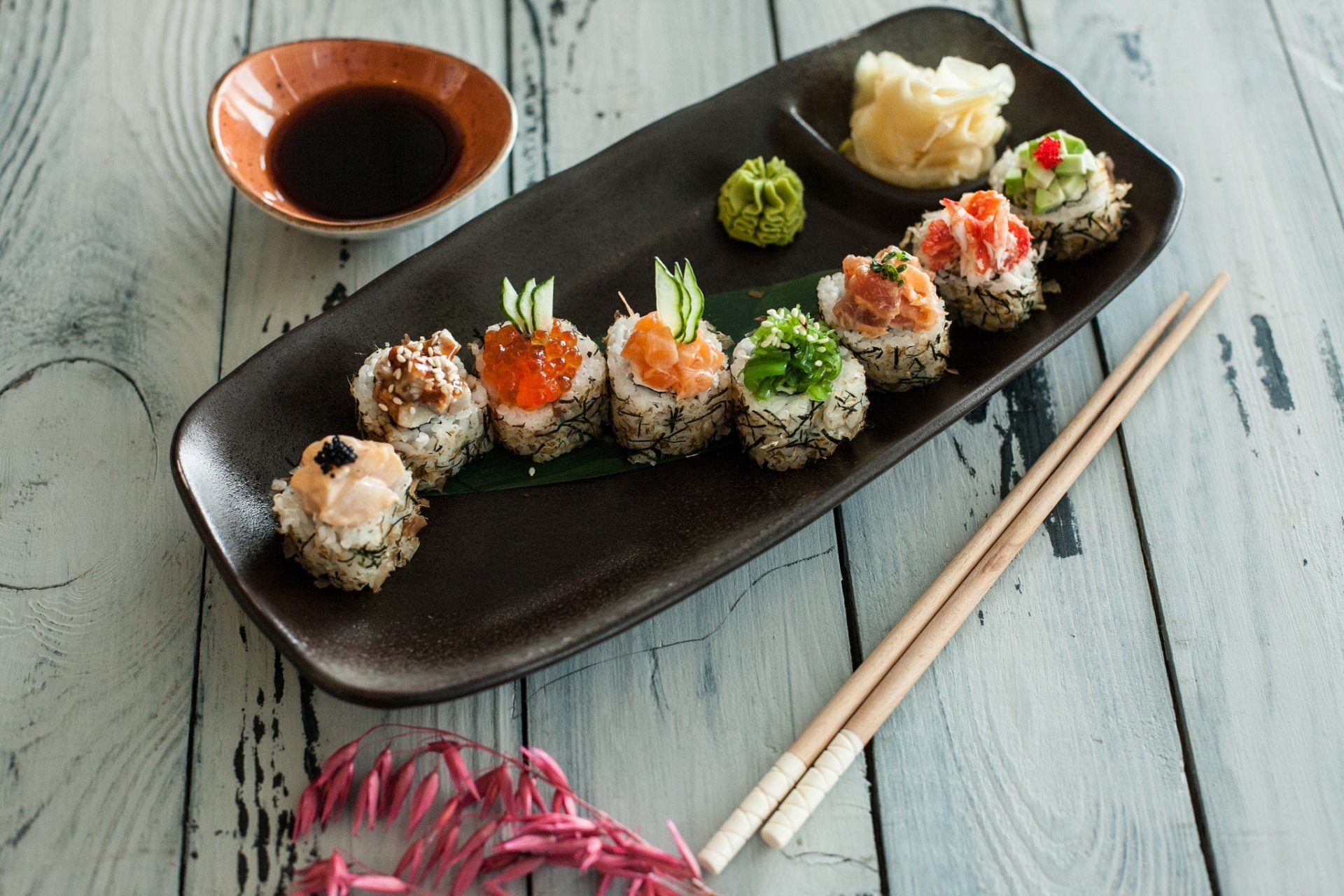 HD PC desktop wallpaper still life of sushi rolls with fish and rice, wasabi, pickled ginger, soy sauce and chopsticks on a rustic wooden table.