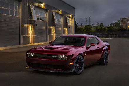 HD desktop wallpaper of a Dodge Challenger SRT Hellcat. The red muscle car is parked in front of a modern building under evening skies, showcasing its sleek design and powerful presence.