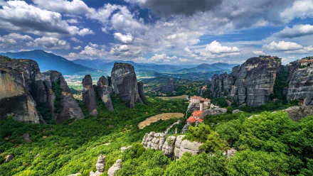 A breathtaking HD wallpaper of Meteora, Greece, showcasing towering rock formations, lush forest, and a historic religious monastery beneath a dramatic mountain sky.