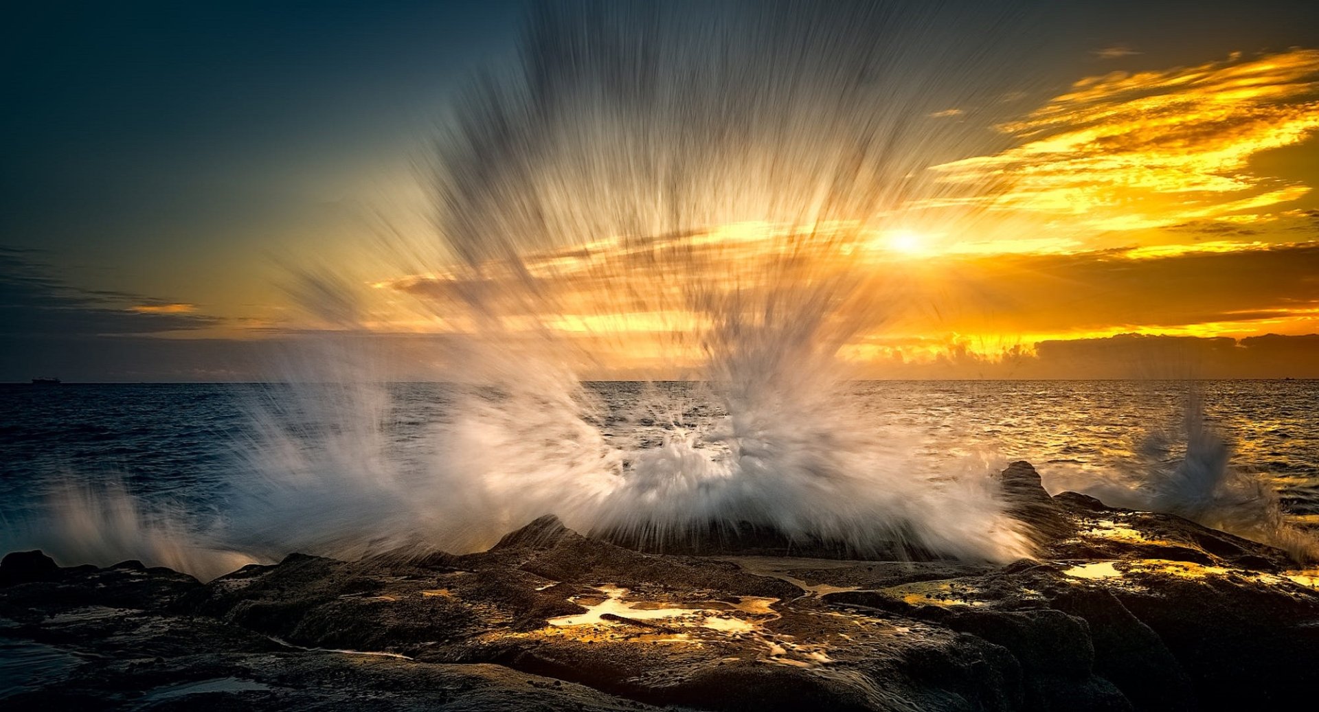 HD PC desktop wallpaper of sunrise over the ocean horizon: golden sky and Ocean Waves crashing on rocky shore, a dramatic nature seascape.