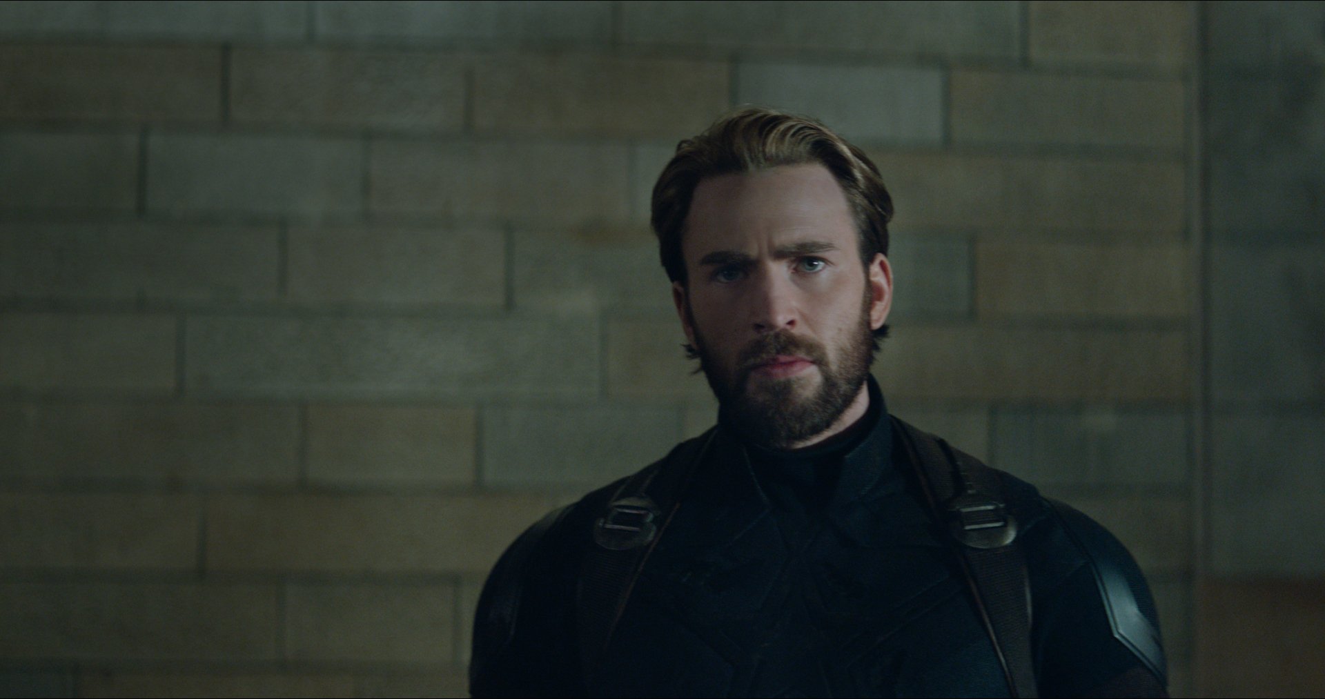 HD wallpaper featuring Chris Evans as Captain America (Steve Rogers) from the movie Avengers: Infinity War. Evans is seen in his superhero costume against a brick wall background.