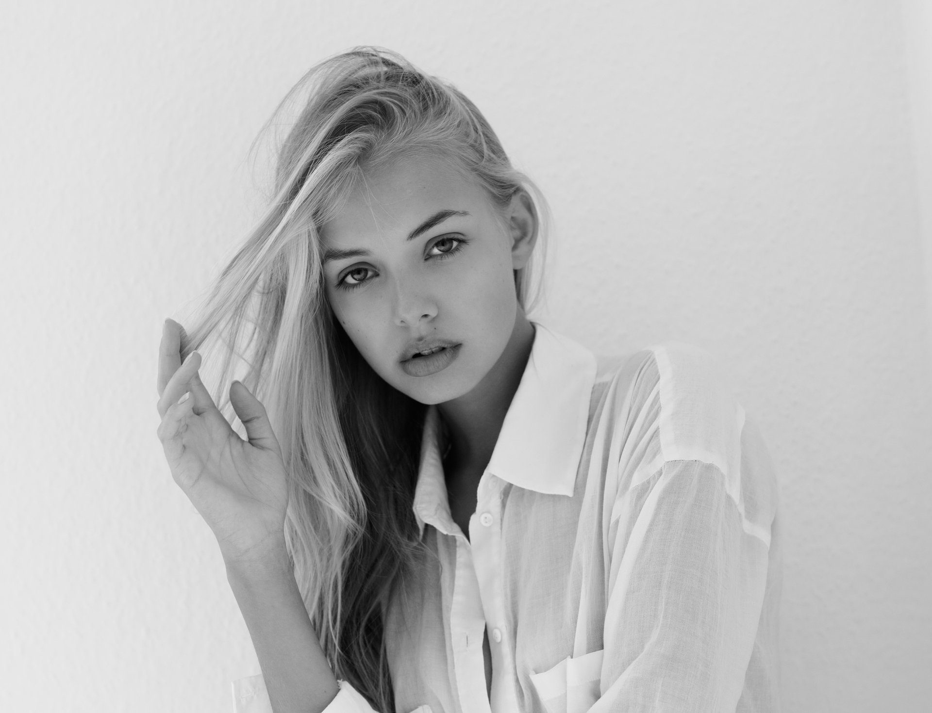 Monochrome black and white portrait of a female model with long hair, styled simply, set against a plain background in 4K Ultra HD quality.