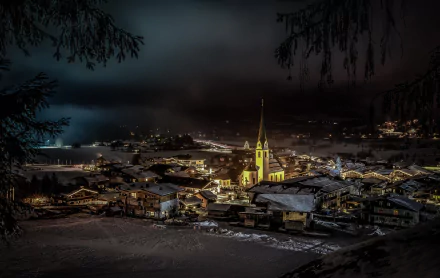 A picturesque winter night in an Austrian village, featuring a beautifully illuminated church surrounded by snow-covered rooftops under a dark sky.