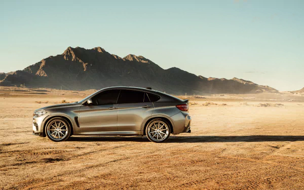 A silver BMW X6 SUV parked on a desert landscape with mountains in the background, captured in 4K Ultra HD for a PC desktop wallpaper.