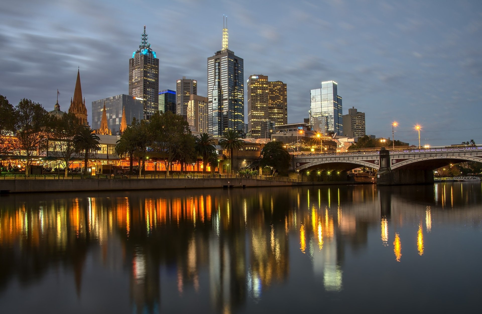 Night view of Melbourne’s city skyline with illuminated skyscrapers reflecting on the Yarra River, showcasing man-made architectural beauty in Australia.