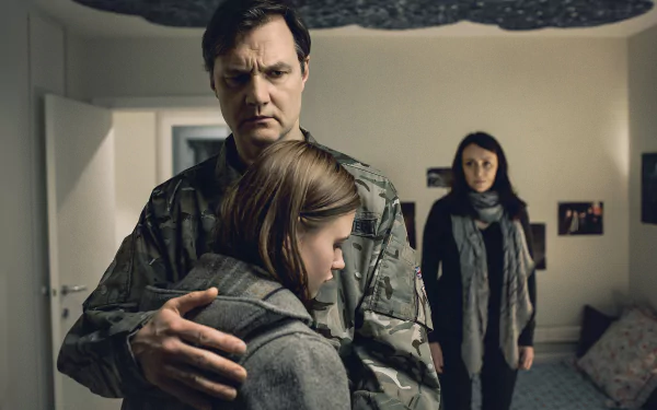 HD desktop wallpaper from The Missing featuring a somber moment as a man in military attire hugs a young girl, with a woman looking on in the background.