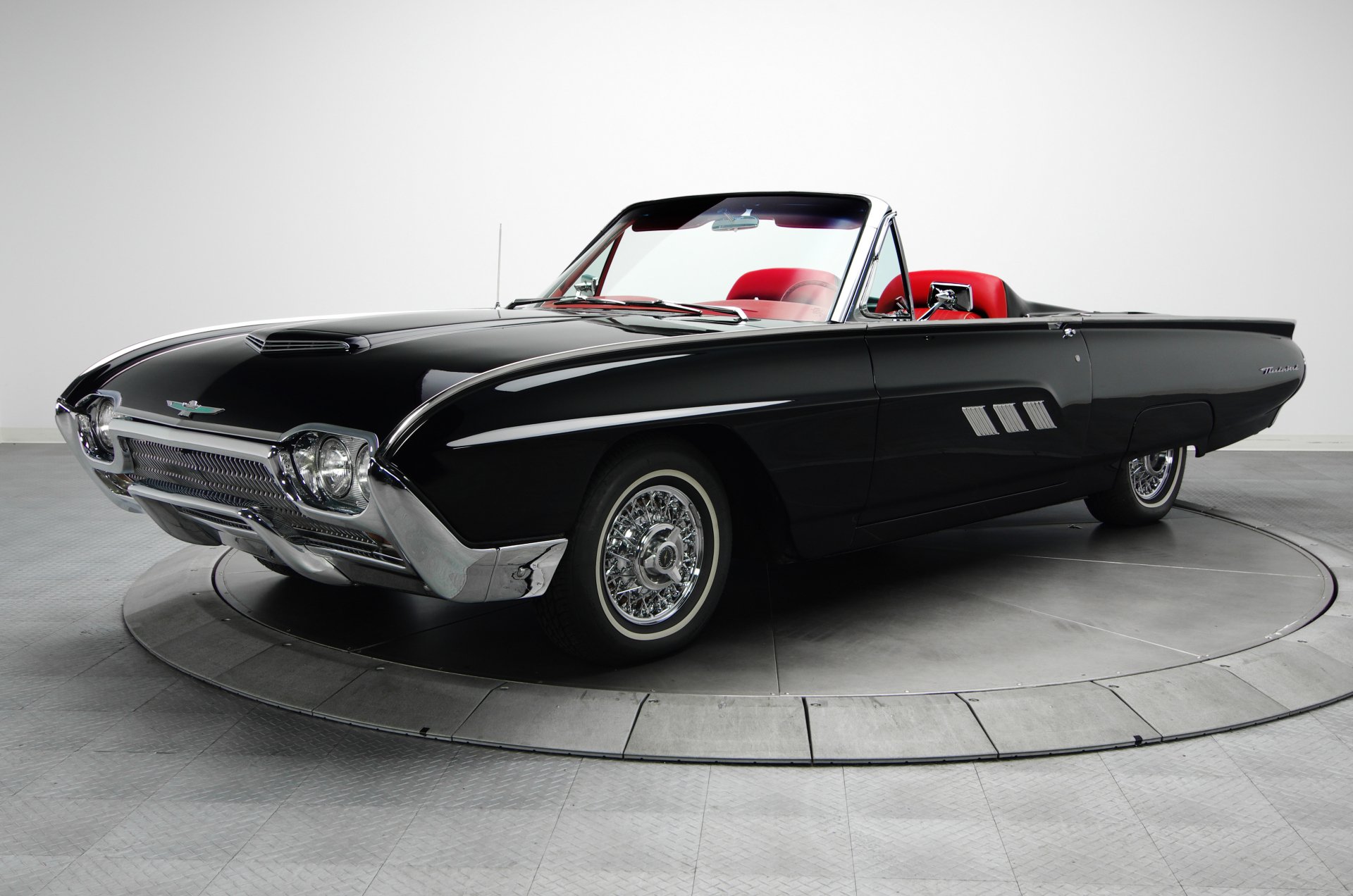 Classic black Ford Thunderbird roadster with red interior on a circular studio turntable — 4K Ultra HD PC desktop wallpaper and background.