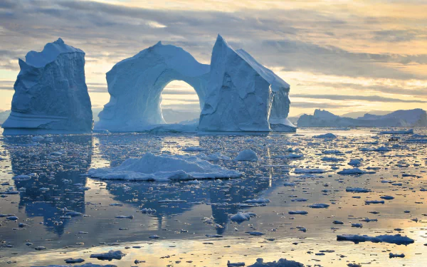 HD desktop wallpaper showcasing a stunning iceberg with a natural arch reflected in calm water, capturing the serene beauty of nature and its icy landscape.