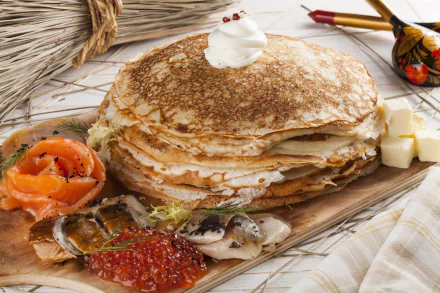 HD desktop wallpaper of a still life featuring a stack of crêpes topped with cream, accompanied by caviar, smoked fish, and small cubes of butter.