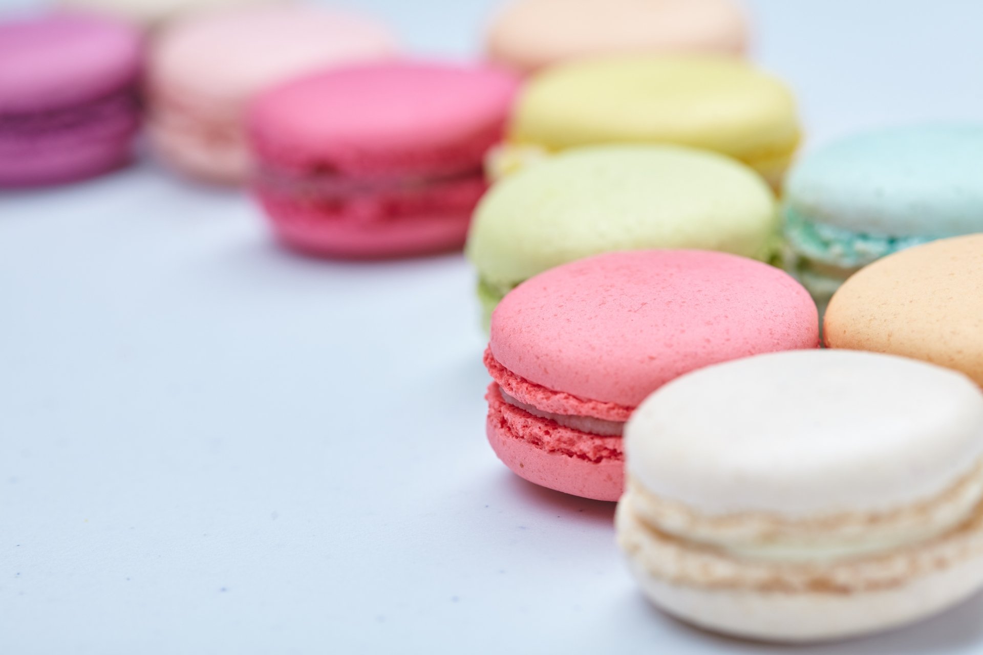 Close-up of colorful macarons arranged on a light surface, captured in stunning 4K Ultra HD, making an appealing sweet food desktop wallpaper and background.