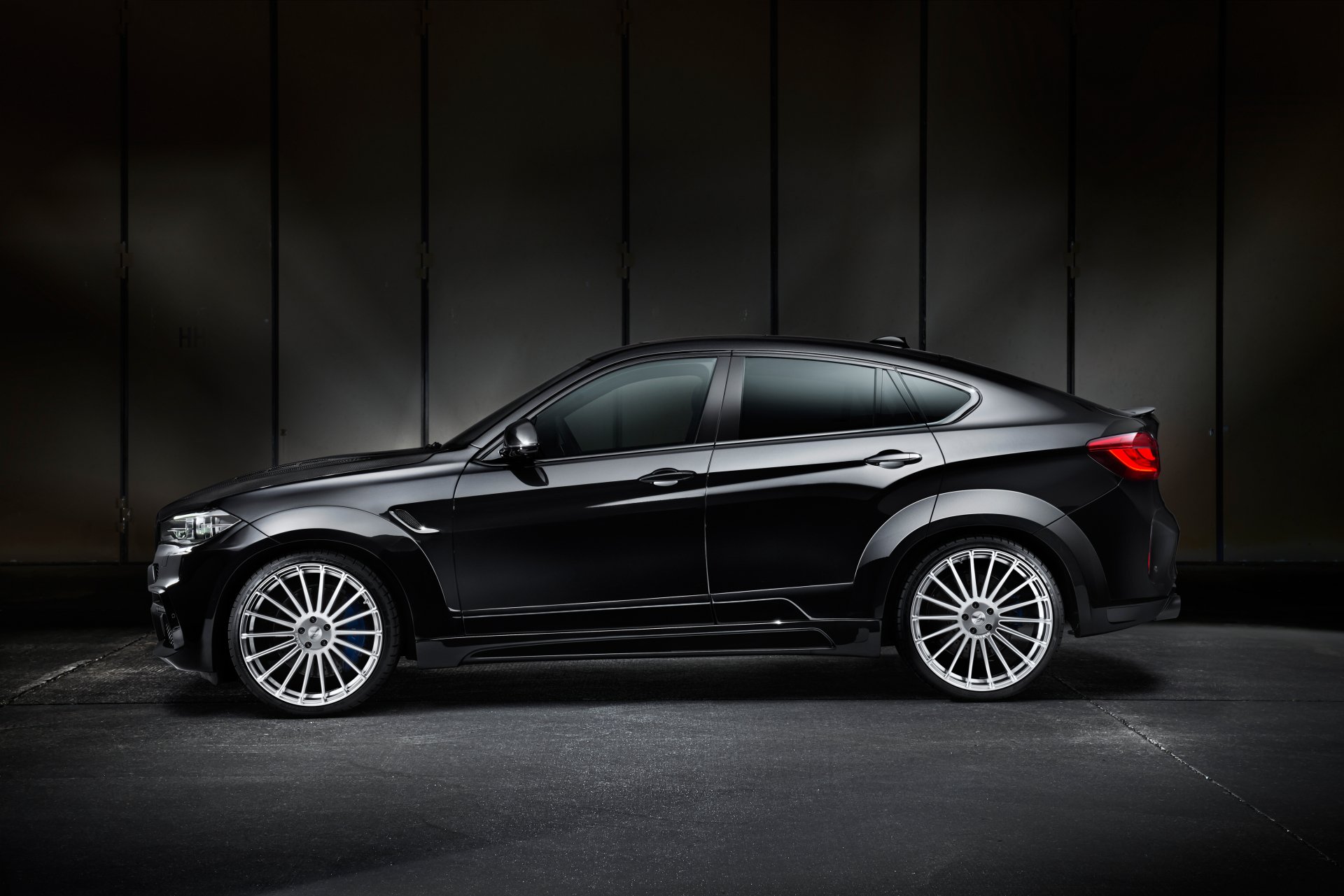 Side-profile of a sleek black BMW X6 SUV parked against a dark industrial backdrop, high-resolution 4K Ultra HD PC desktop wallpaper.