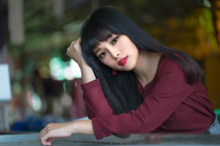 Portrait of an Asian woman with black hair and brown eyes, wearing lipstick, captured with a soft depth of field in a richly colored setting.