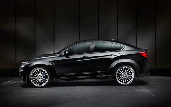 Side-profile of a sleek black BMW X6 SUV parked against a dark industrial backdrop, high-resolution 4K Ultra HD PC desktop wallpaper.