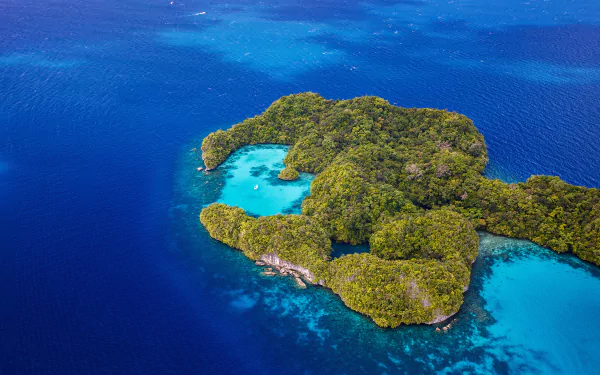 Aerial view of a lush tropical island surrounded by a vibrant blue lagoon and ocean, captured in high definition as a stunning PC desktop wallpaper background.
