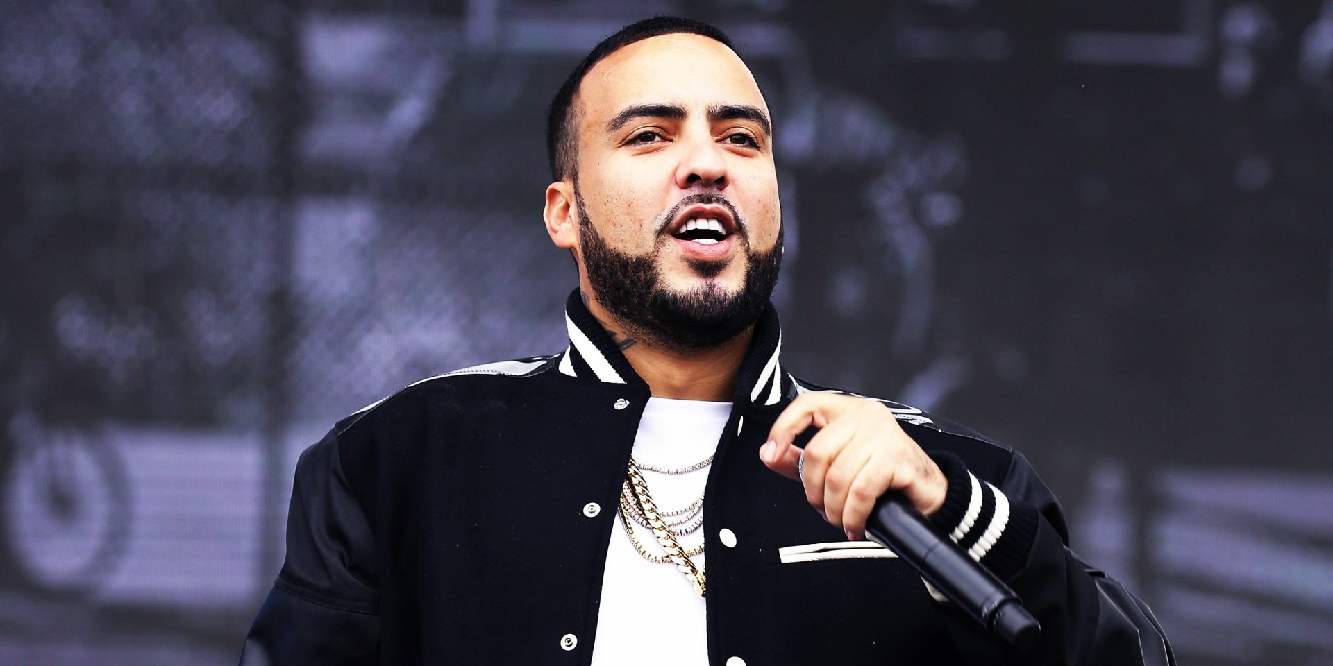 HD wallpaper of a man performing on stage, wearing a black jacket with a microphone in hand, set against a blurred background.