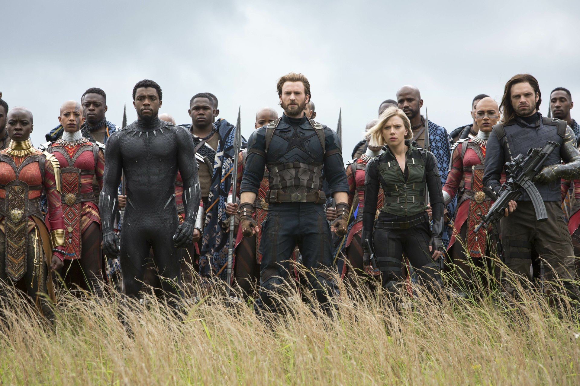 HD wallpaper featuring Captain America, Black Panther, Black Widow, and the Winter Soldier alongside Okoye and other warriors from Avengers: Infinity War, standing in a field ready for battle.