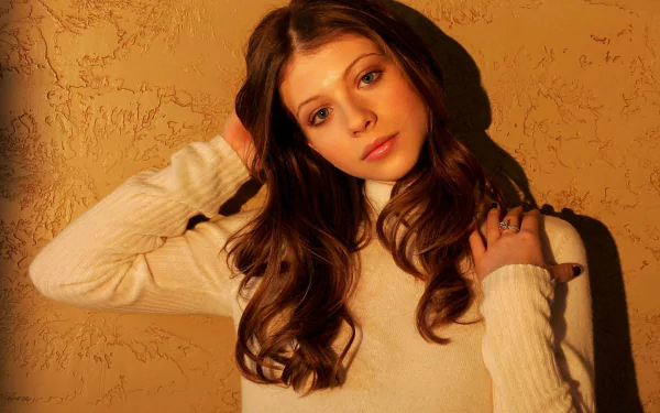 HD desktop wallpaper featuring actress and celebrity Michelle Trachtenberg against a textured warm-toned background, wearing a light-colored sweater.