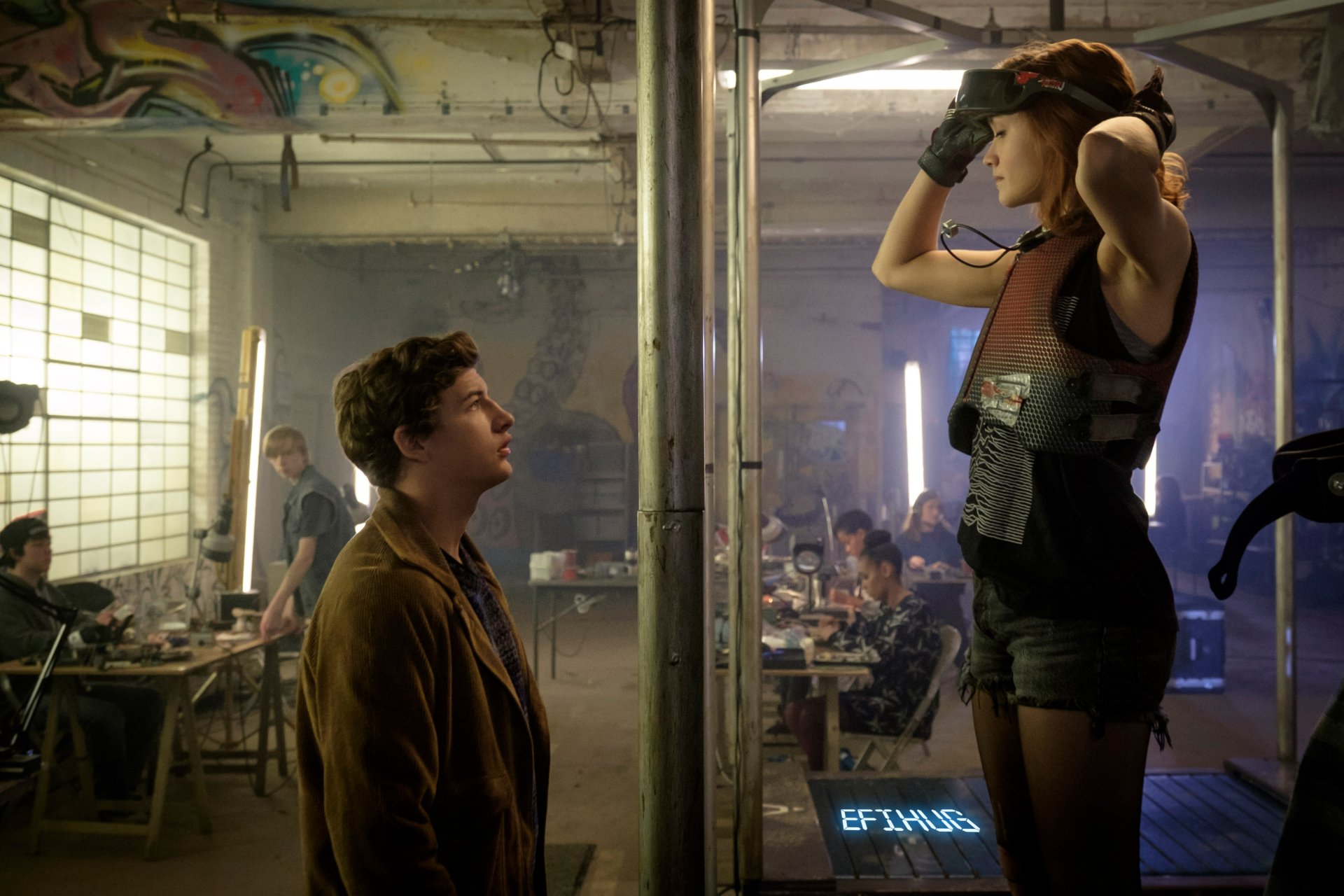 HD desktop wallpaper from the movie Ready Player One featuring Olivia Cooke and Tye Sheridan in a futuristic workshop setting.