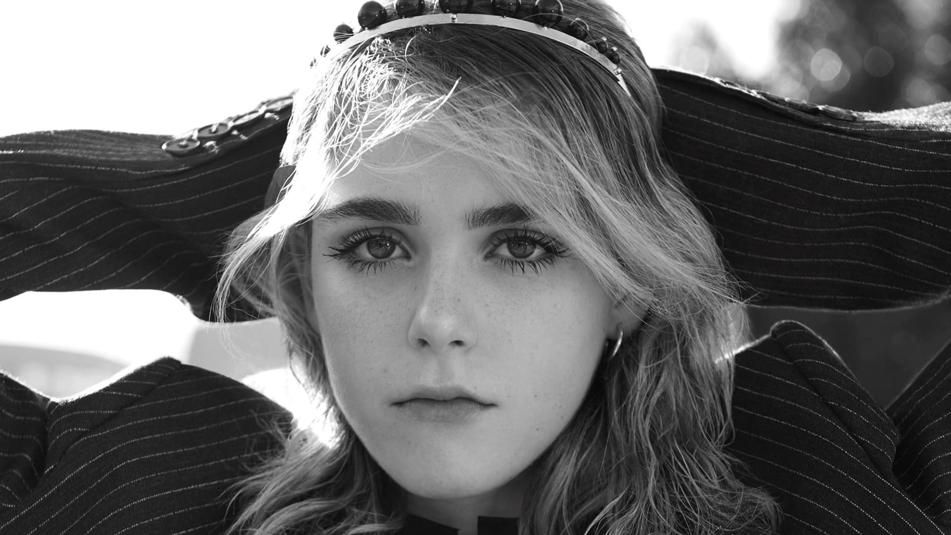 Monochrome HD PC desktop wallpaper: close-up portrait of a young actress with wide-brim hat, wavy hair and intense gaze, celebrity editorial styling.