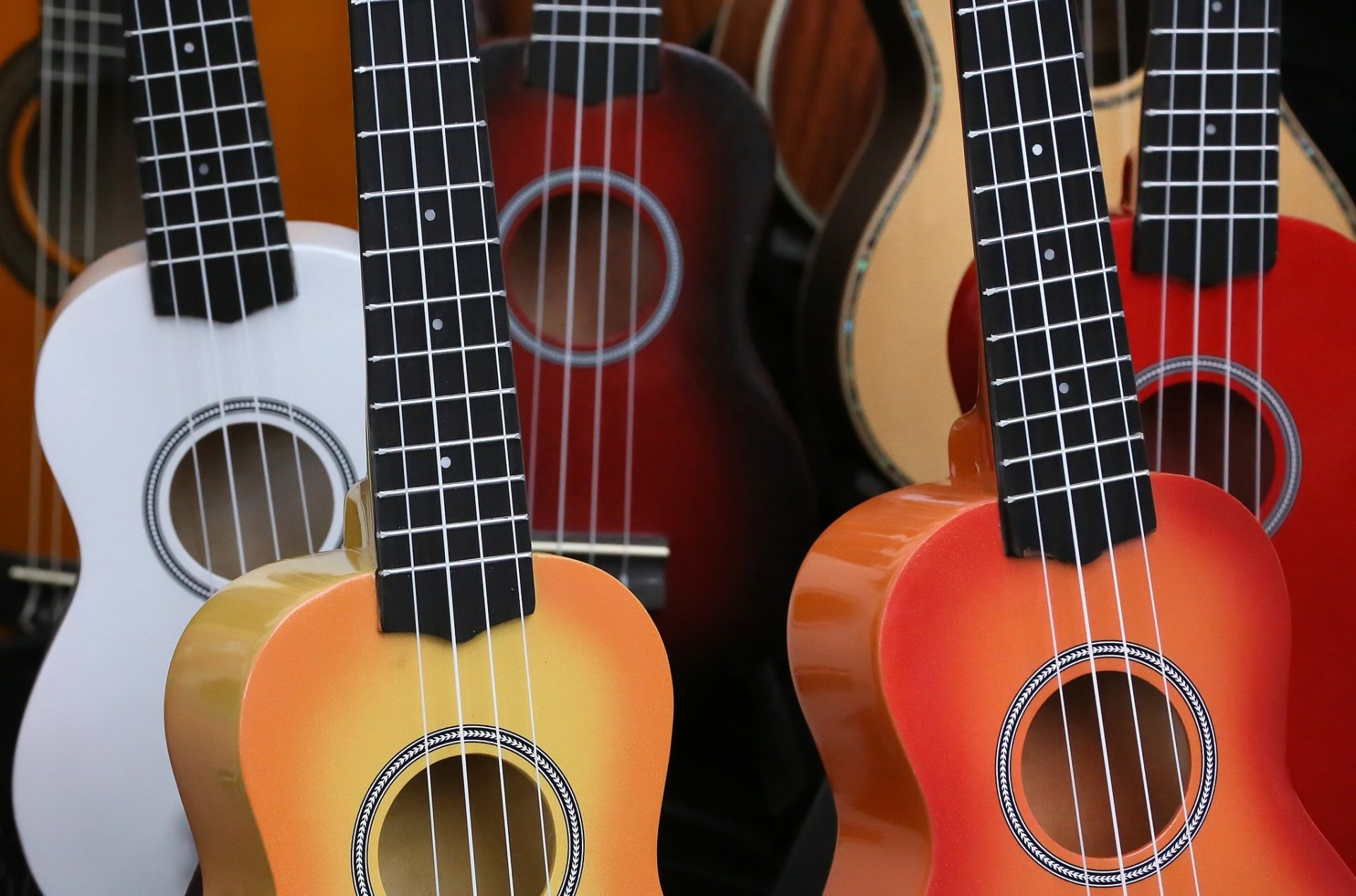 HD PC desktop wallpaper: close-up of colorful acoustic guitars—orange, red, white instruments, music-themed background.