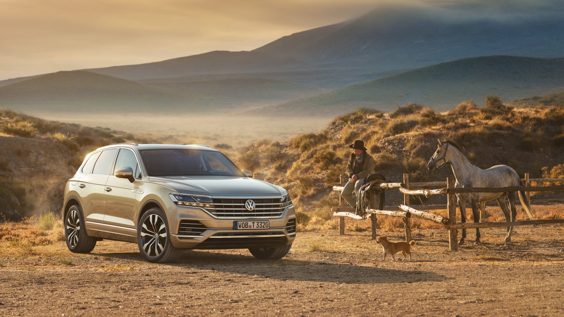 A silver Volkswagen Touareg SUV parked near a cowboy tending to horses in a dusty, mountainous landscape at sunset, captured in 4K Ultra HD resolution.