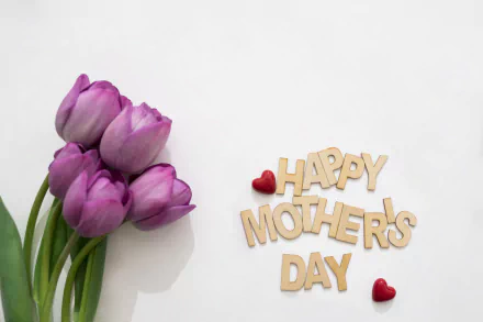 A bouquet of pink tulips alongside wooden letters spelling Happy Mother's Day with two small red heart decorations, shown in a 4K Ultra HD desktop wallpaper style.
