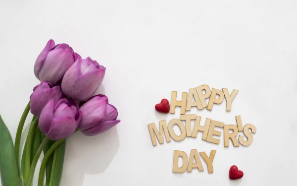 A bouquet of pink tulips alongside wooden letters spelling Happy Mother's Day with two small red heart decorations, shown in a 4K Ultra HD desktop wallpaper style.