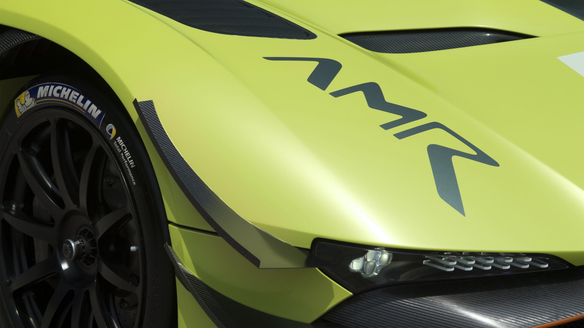 Close-up of a vibrant yellow Aston Martin Vulcan AMR Pro showcasing its sleek front design and Michelin tires in a 4K Ultra HD desktop wallpaper background.