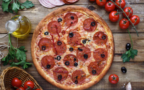 HD PC desktop wallpaper featuring a still life of a pepperoni pizza with olives, fresh tomatoes, olive oil, and herbs on a rustic wooden surface.