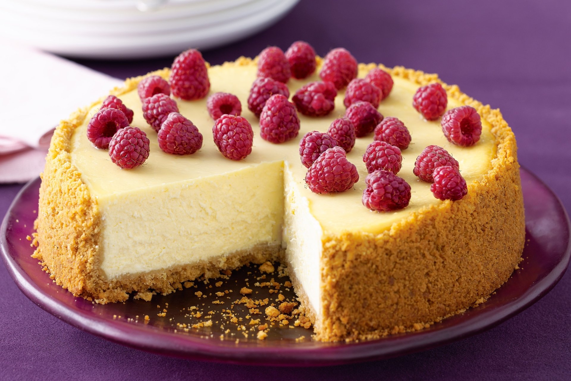 A creamy cheesecake topped with fresh raspberries on a crumbly pastry crust, displayed as an HD PC desktop wallpaper background.