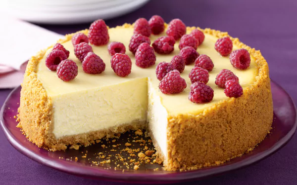 A creamy cheesecake topped with fresh raspberries on a crumbly pastry crust, displayed as an HD PC desktop wallpaper background.