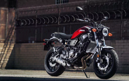 Yamaha XSR700 motorcycle vehicle parked against an urban brick wall — 2K Quad HD PC desktop wallpaper/background, red tank and retro-modern styling.