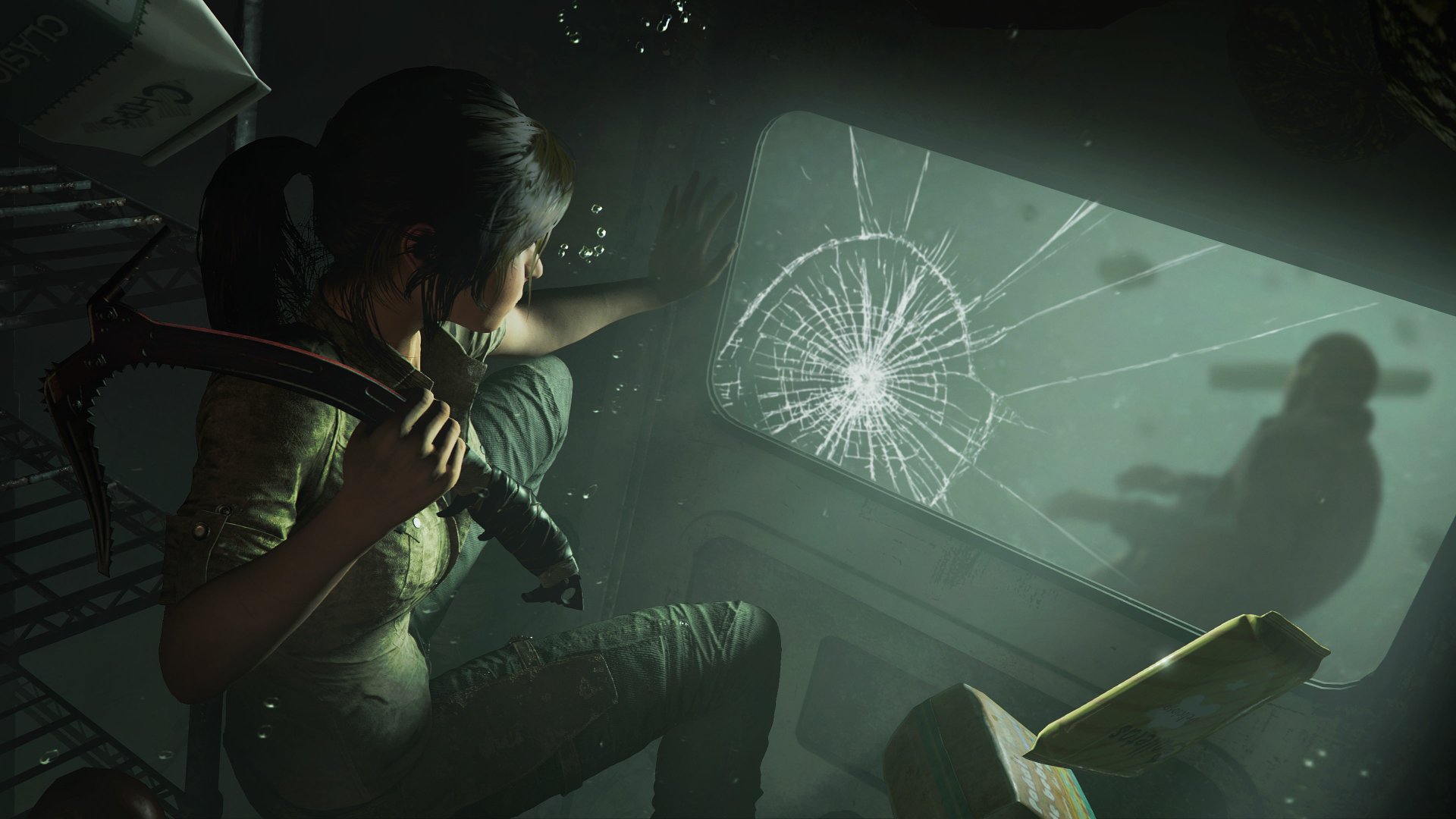 Lara Croft from Shadow of the Tomb Raider crouches inside a dimly lit, cracked-glass vehicle, holding a flashlight in this 4K Ultra HD video game desktop wallpaper.
