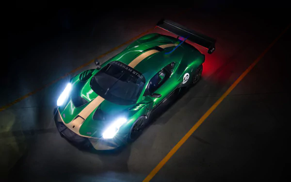 A striking 4K Ultra HD wallpaper of a green and gold Brabham BT62 race car with illuminated headlights parked on a dark track.