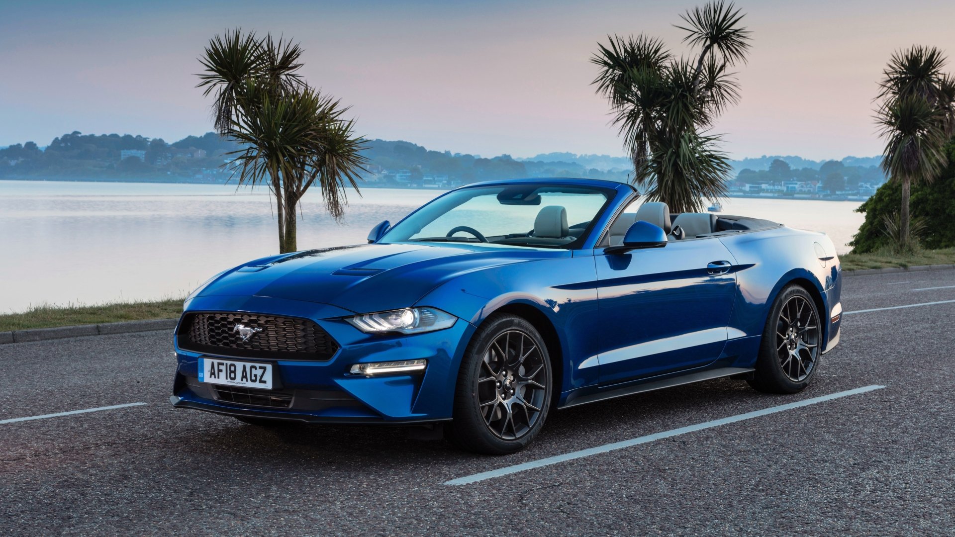 Blue Ford Mustang cabriolet parked by a calm waterfront at sunrise, 4K Ultra HD PC desktop wallpaper background showcasing the sporty Ford car vehicle.