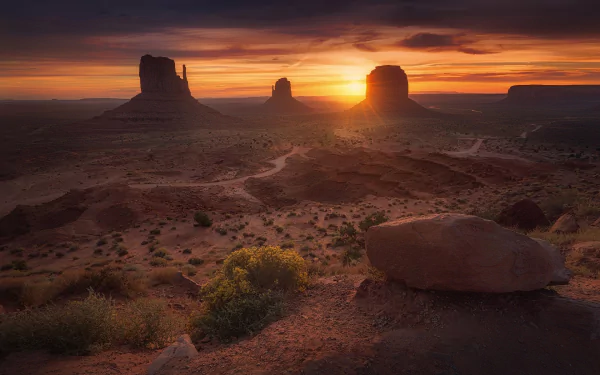 A stunning sunrise illuminates the iconic rock formations of Monument Valley, showcasing the beauty of the desert landscape in this breathtaking HD wallpaper.