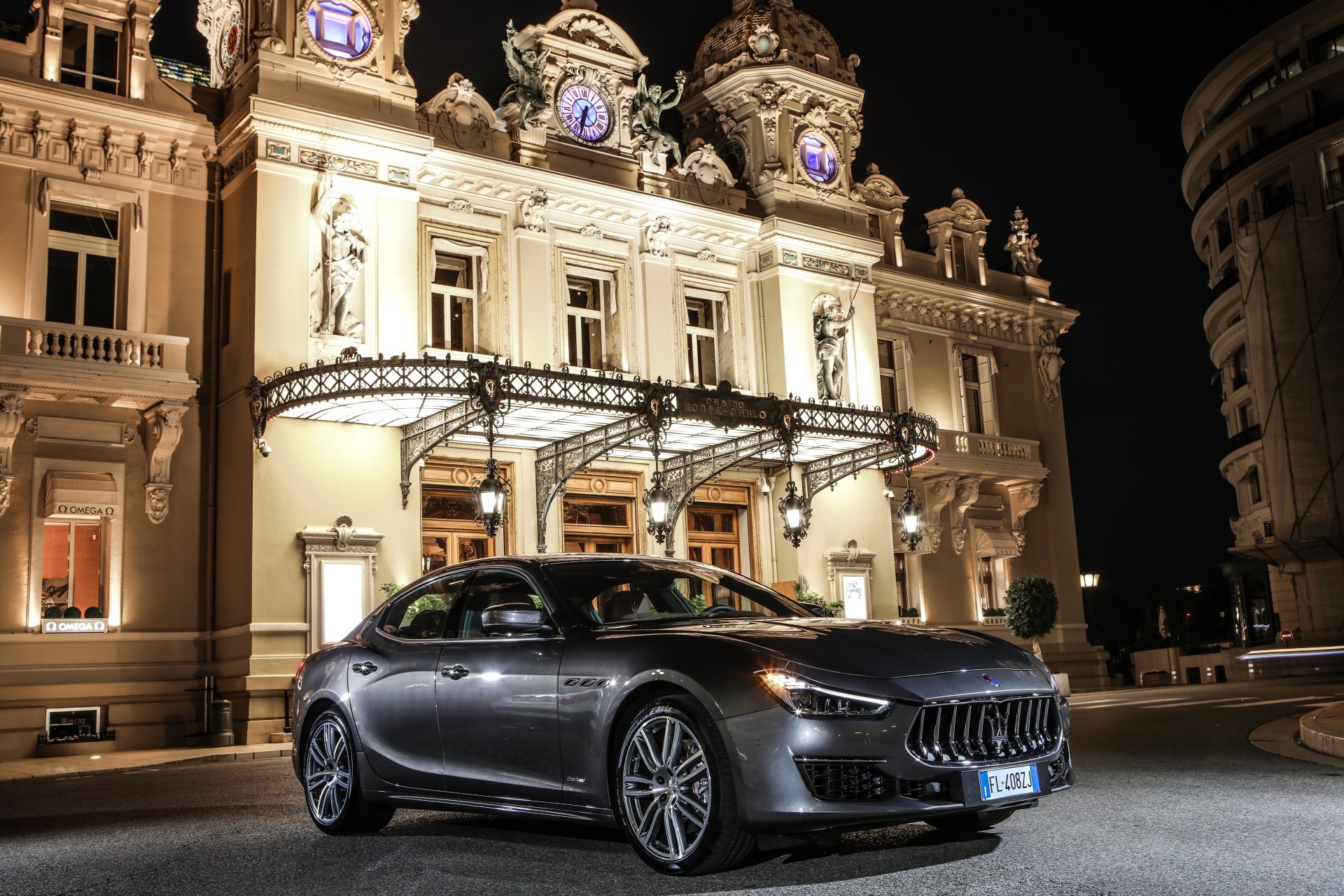 A sleek silver Maserati Ghibli parked at night in front of an ornate, illuminated building, captured in 4K Ultra HD for a stunning PC desktop wallpaper.