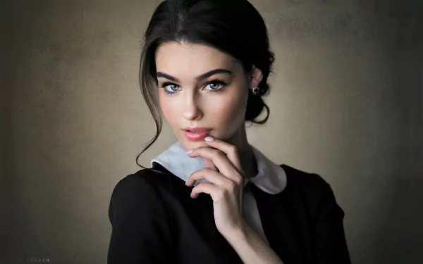 HD desktop wallpaper featuring a model with striking blue eyes and black hair, posing thoughtfully against a muted background.